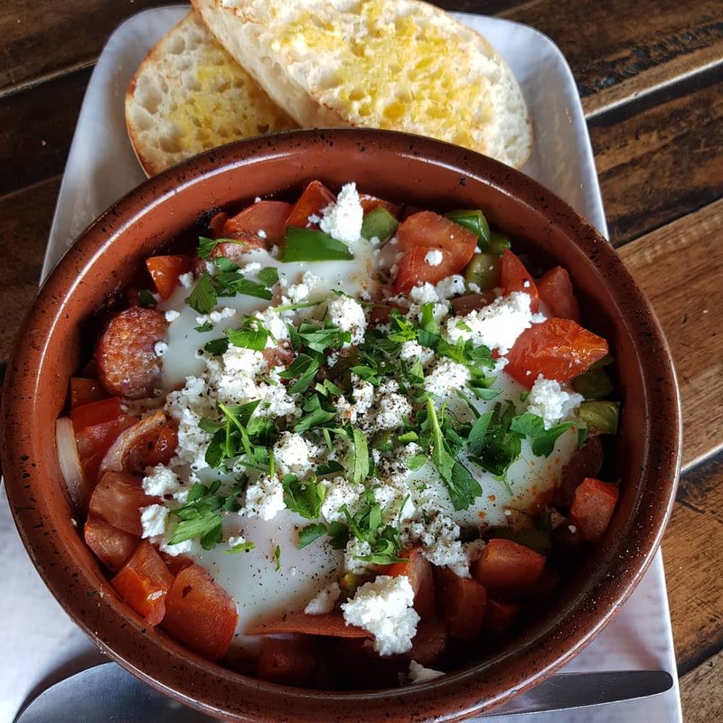 Shakshuka in a clay pot with feta and parsley
